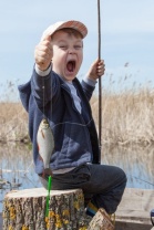 Happy boy holding a fish caught in the pond 28062560_s